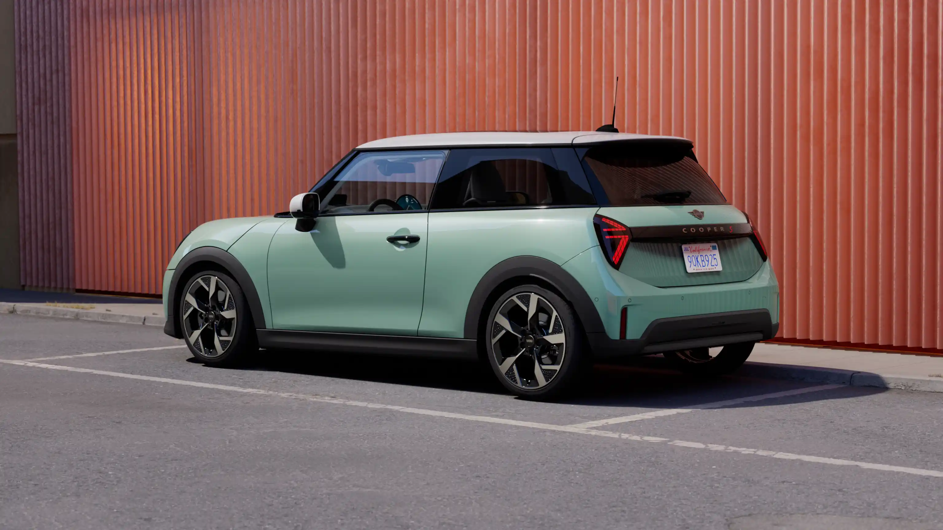 Rear left view of a parking MINI Cooper in Ocean Wave Green with White Roof