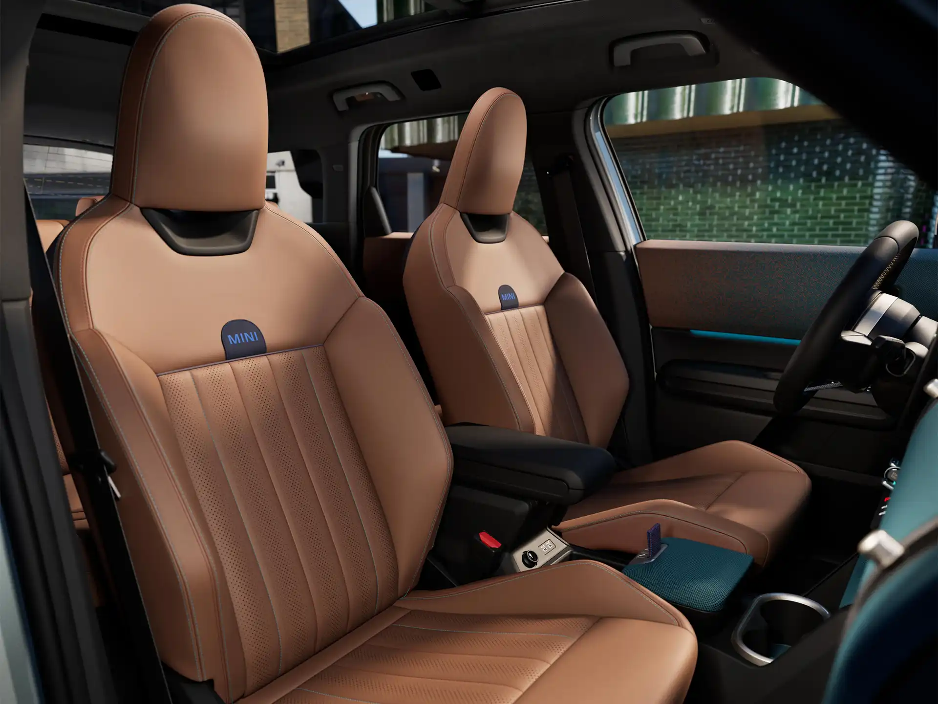 Interior perspective of the all-electric MINI Countryman is showing the dashboard, steering wheel, round display, panorama glassroof  and back of the frontseats.