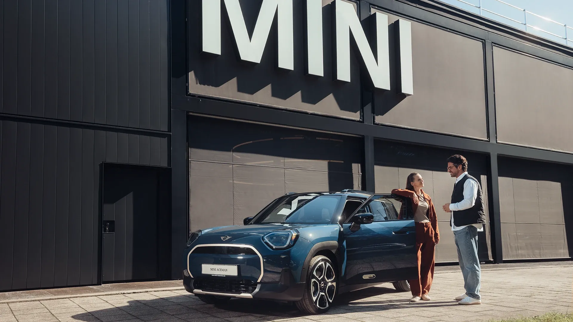 MINI Service Partner premises with a customer driving her new MINI Electric out onto the forecourt