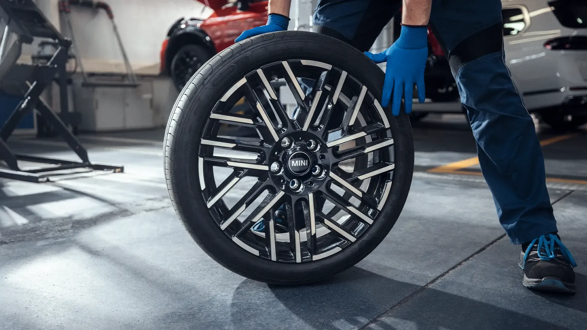MINI Wheels and Tyres Service – MINI technician rolls a MINI wheel into storage facilities.