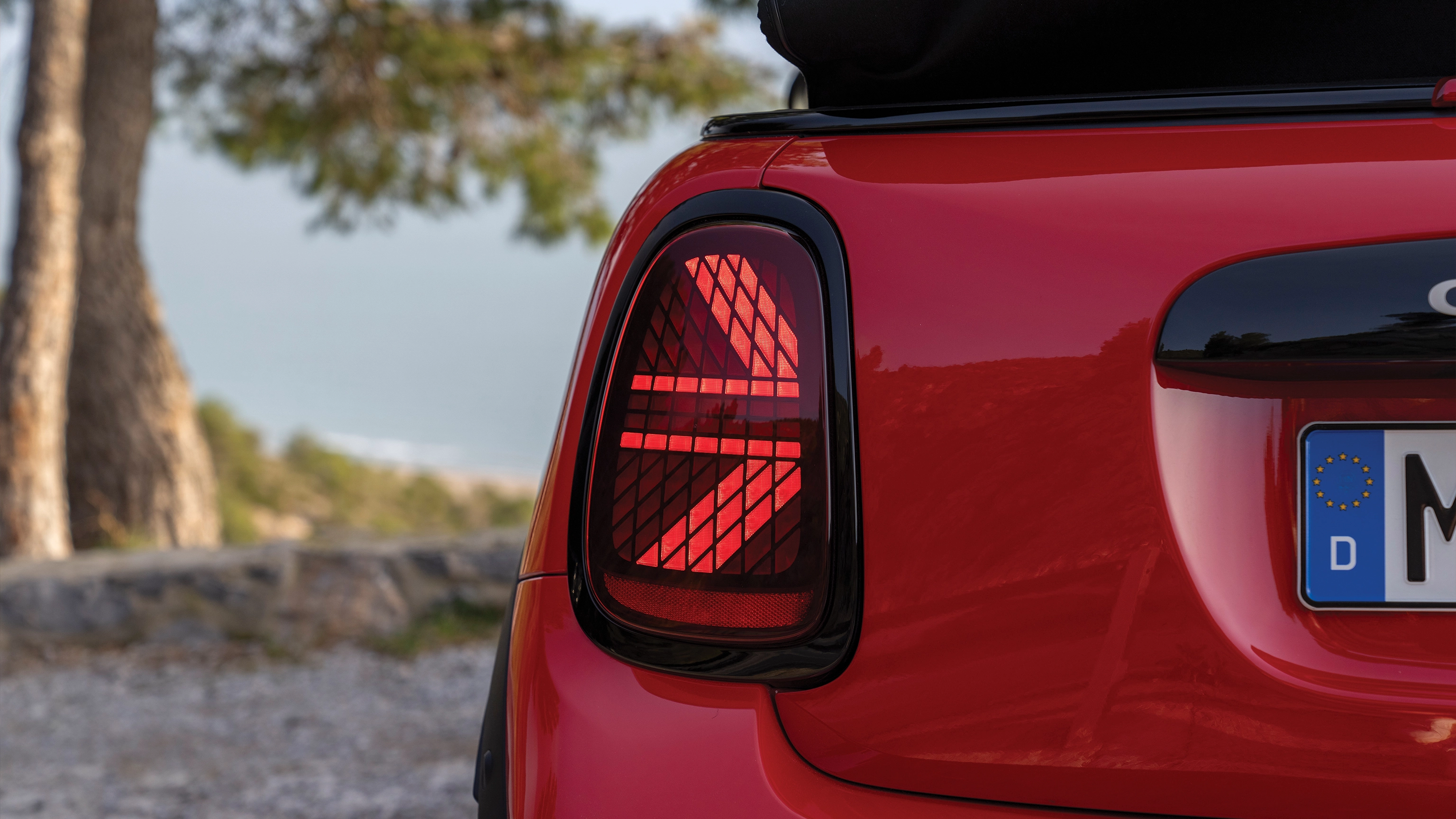 Rear view of a driving MINI Cooper Convertible in Copper Grey 