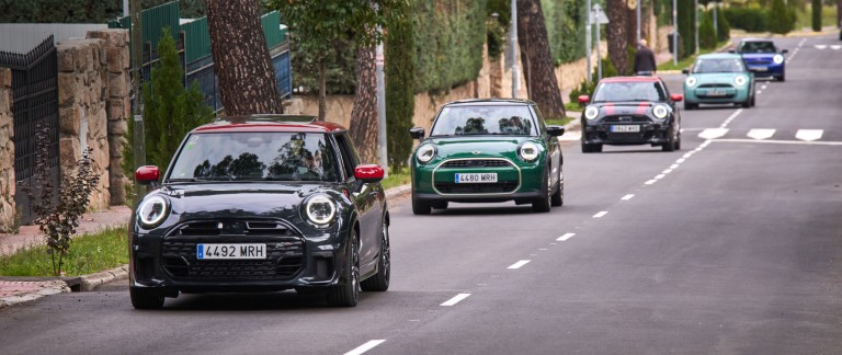 A group of MINI cars driving in a line on a scenic road